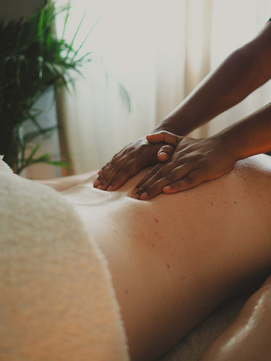 Les mains de la masseuse massent le dos de la cliente en suivant la colonne dorsale.